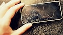Hand hält ein kaputtes Smartphone-Display