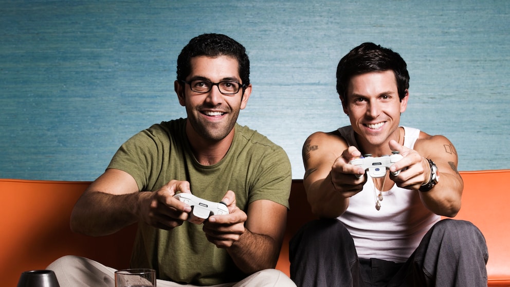 Zwei Männer sitzen auf dem Sofa und Spielen Playstation
