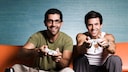 Zwei Männer sitzen auf dem Sofa und Spielen Playstation