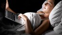 Frau liegt im Bett mit Laptop