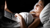 Frau liegt im Bett mit Laptop