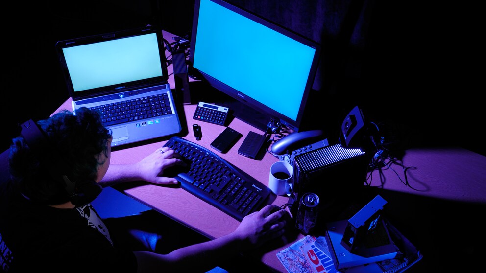 Mann sitzt im Dunkeln vor Computer