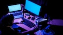 Mann sitzt im Dunkeln vor Computer