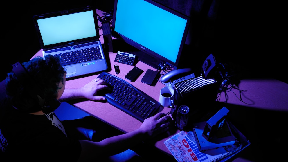Mann sitzt im Dunkeln vor Computer