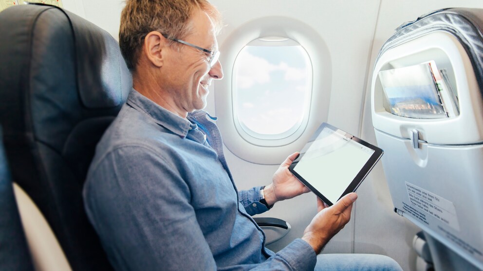 Mann mit Tablet im Flugzeug