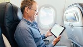 Mann mit Tablet im Flugzeug