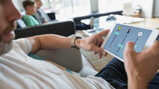Mann auf Couch steuert sein smartes Zuhause