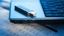 USB-Stick liegt auf einem Laptop mit USB-Buchsen