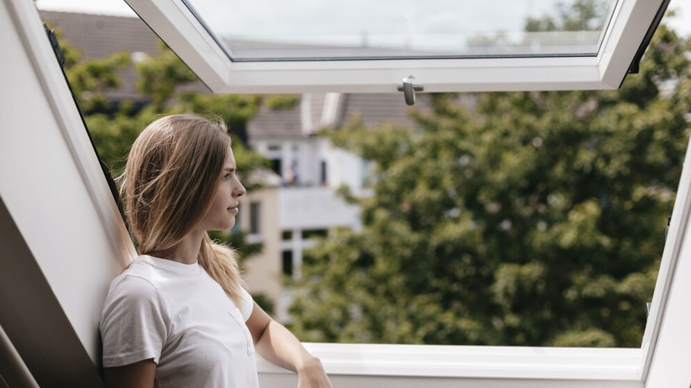 Blonde Frau steht am Fenster