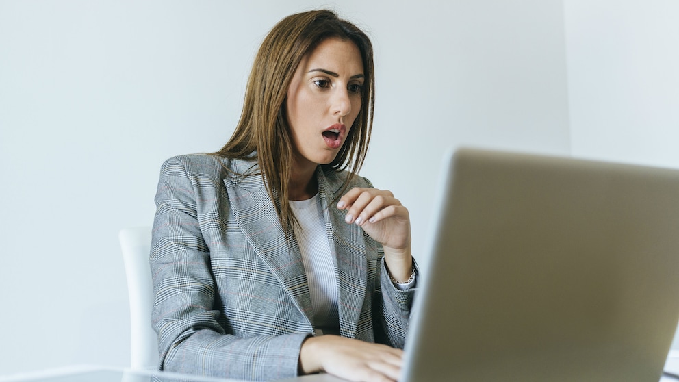 Frau schaut schockiert auf den Laptop
