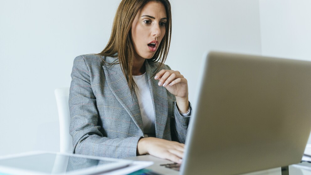 Frau schaut schockiert auf den Laptop