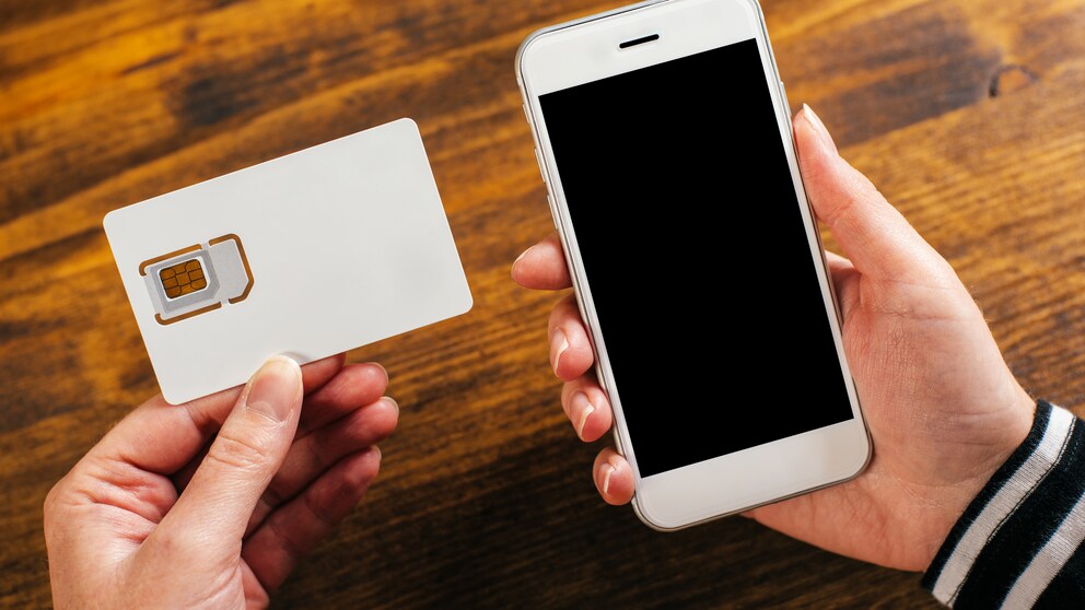 Frau hält Smartphone und Simkarte in der Hand