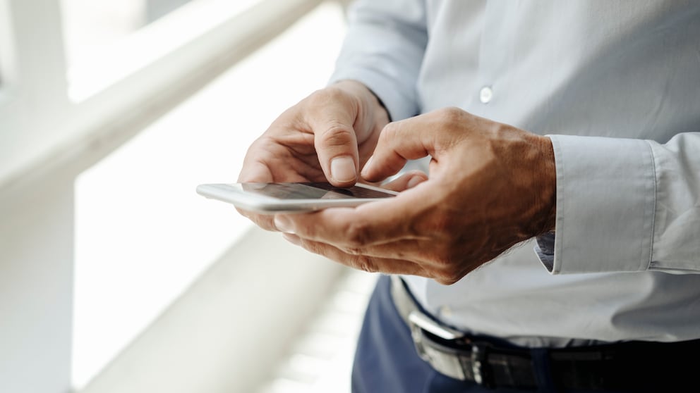 Ein Mann mit Smartphone in der Hand beim Tippen