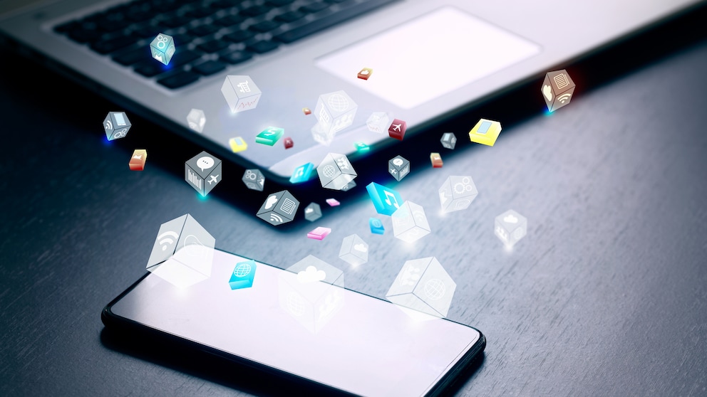 Smartphone und Laptop auf einem Tisch mit zahlreichen Apps