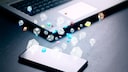Smartphone und Laptop auf einem Tisch mit zahlreichen Apps