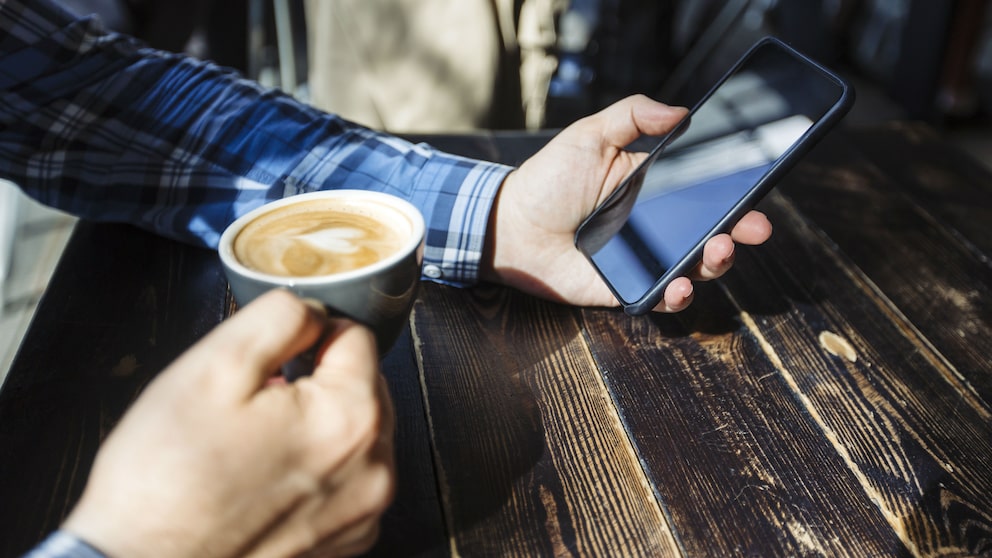 Mann mit Tasse und iPhone