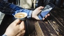 Mann mit Tasse und iPhone