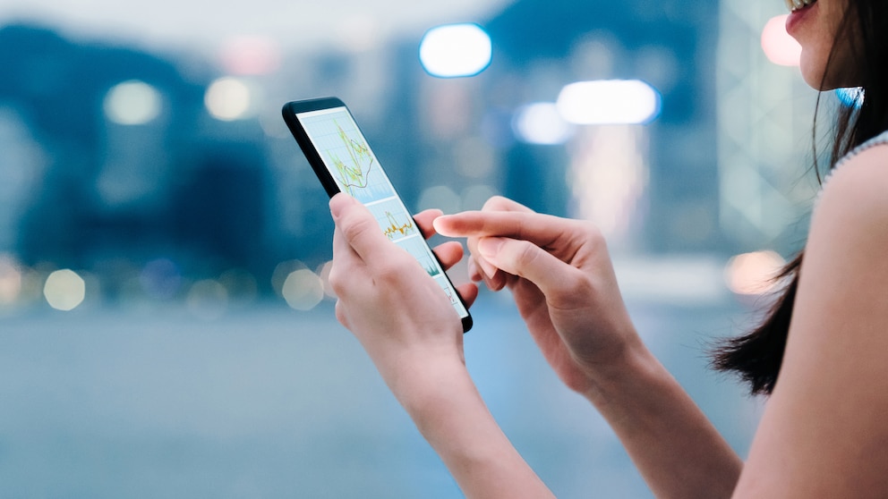 Frau mit einem Smartphone in der Hand, Hintergrund unscharf