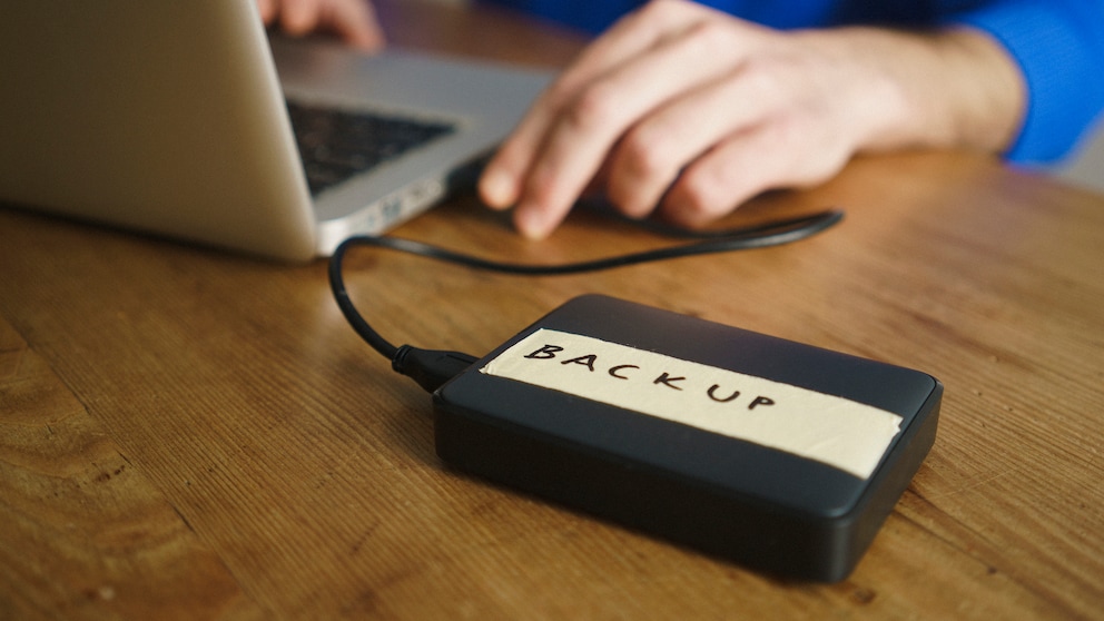 Mann macht Laptop-Backup auf externer Festplatte