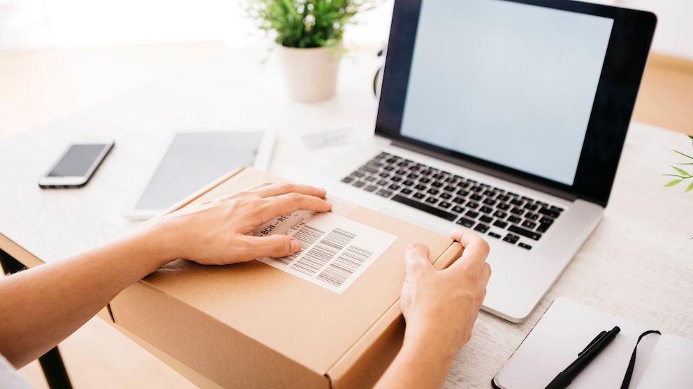 Frau mit Laptop und Paket auf Schreibtisch