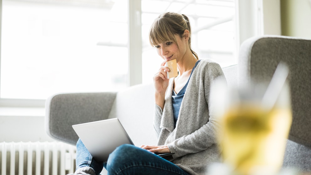 Frau sitzt auf der Couch mit einem Laptop und shoppt online