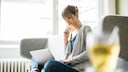 Frau sitzt auf der Couch mit einem Laptop und shoppt online