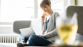 Frau sitzt auf der Couch mit einem Laptop und shoppt online