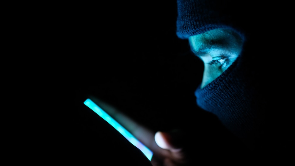 Maskierter Hacker mit Smartphone