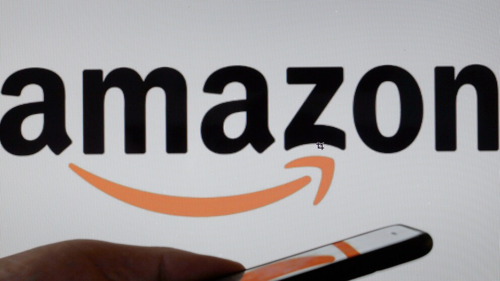 Hand hält Handy vor einem Amazon-Logo