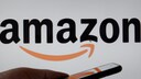 Hand hält Handy vor einem Amazon-Logo