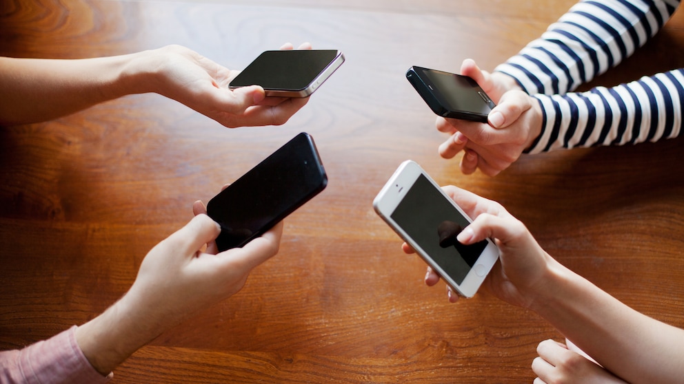 4 friends sharing on smart phones.