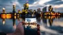Mann hält Smartphone in der Hand, auf dem Display sieht man die Skyline von Wien