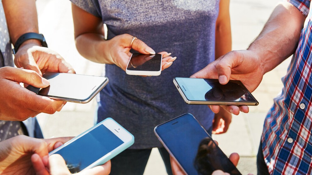 junge Menschen in einem kreis mit ihren Smartphones