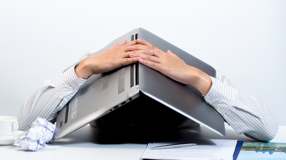 Mann versteckt sich unter Laptop