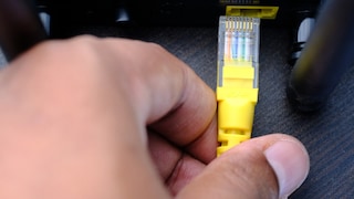 Person zieht Netzwerkstecker aus einem Router