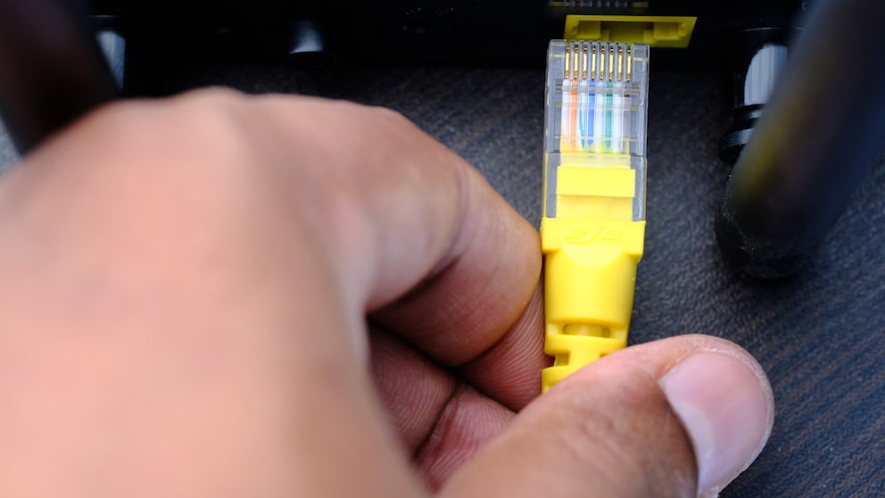 Person zieht Netzwerkstecker aus einem Router