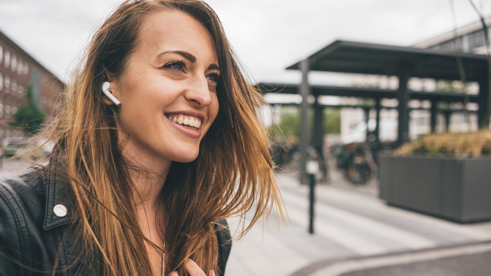 Lächelnde junge Frau trägt Apple AirPods