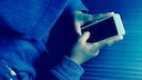 Person mit Hoodie hält ein Handy