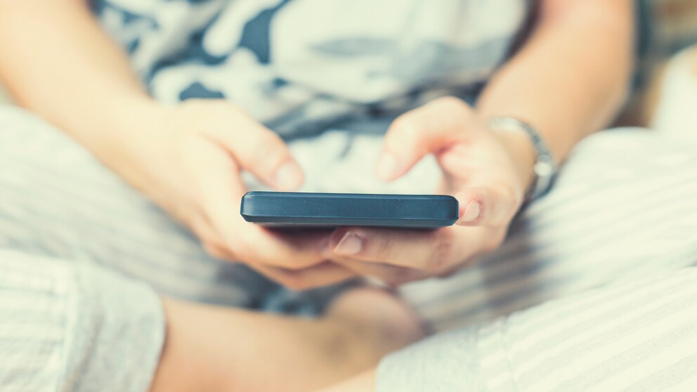 Frau hält Smartphone in den Händen und schreibt auf Instagram