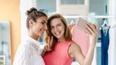 zwei lächelnde junge Frauen machen zusammen ein Selfie