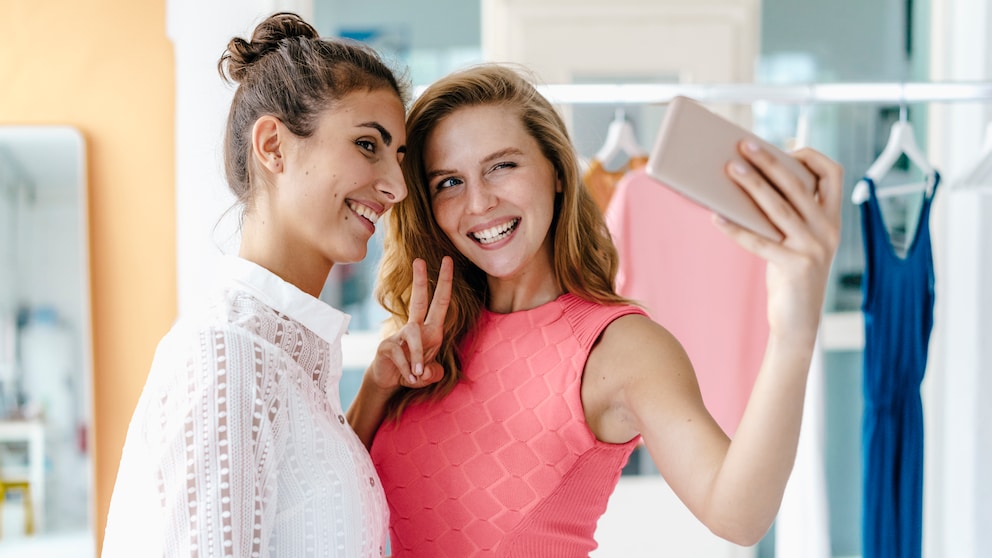 zwei lächelnde junge Frauen machen zusammen ein Selfie