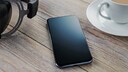 Smartphone mit Kopfhörern und Heißgetränk auf Tisch