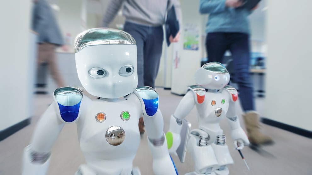 Zwei Roboter laufen im Büro neben Menschen