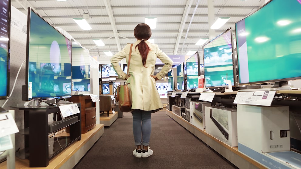 Frau im Elektronikmarkt vor Fernsehern
