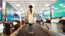 Frau im Elektronikmarkt vor Fernsehern
