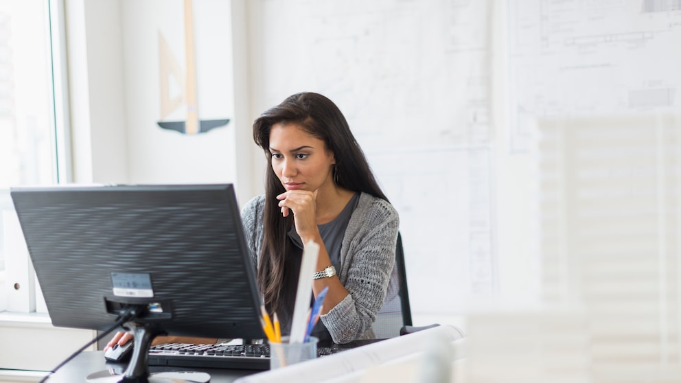 Frau sitzt vor einem Computer-Monitor