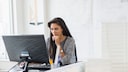 Frau sitzt vor einem Computer-Monitor