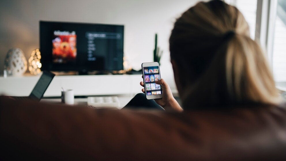 Frau sitzt auf Sofa und schaut fernsehen