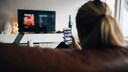 Frau sitzt auf Sofa und schaut fernsehen