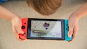 Kind liegt auf dem Boden und spielt mit der Nintendo Switch